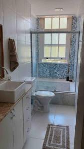 a bathroom with a toilet and a sink and a window at Apartamento encantador no Palácio Quitandinha in Petrópolis