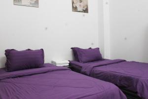 two beds in a room with purple sheets at Kuantan Homestay Best Facility Wifi BBQ Viu in Kuantan
