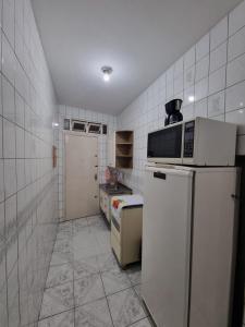 a small kitchen with a refrigerator and a microwave at Kitnet Ubatuba in Ubatuba