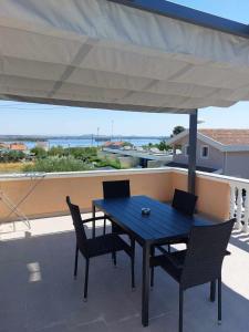 a blue table and chairs on a balcony with an umbrella at Apartments with parking space Kraj, Pasman - 335 in Tkon