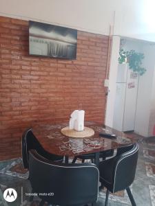 une table et des chaises avec une télévision sur un mur en briques dans l'établissement Shalom, à Mina Clavero