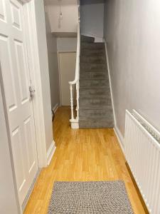 um corredor com uma escada com um tapete e uma porta em Dalston's Rooms em Londres