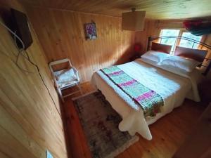 1 dormitorio con 1 cama en una cabaña de madera en Hostal Turismo Allipen, en Melipeuco