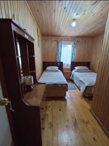 um quarto com 2 camas e piso em madeira em Hostal Turismo Allipen em Melipeuco