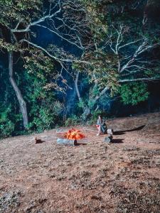 a person sitting around a fire in a field at Cantinhos do Cipó - Chales privativos com hidro in Serra do Cipo