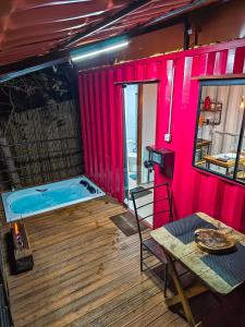 bañera de hidromasaje en una habitación con paredes rosas y mesa en Pousada Cipó Container Chalés Privativos com lareira - Centro da cidade en Serra do Cipo