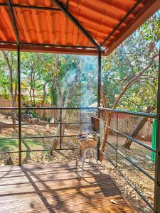 a screened porch with a table and a grill at Pousada Cipó Container Chalés Privativos com lareira - Centro da cidade in Serra do Cipo