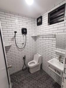 een witte badkamer met een toilet en een wastafel bij Kulim Mini HomeStay in Kulim