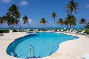 a swimming pool with palm trees and the ocean at Beach Living at Villas Pappagallo BLEV in West Bay