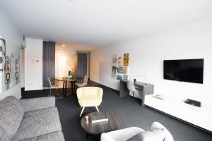 a living room with a couch and a tv at Tyrian Serviced Apartments Fitzroy in Melbourne