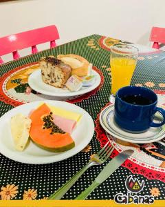 a table with two plates of food and a cup of orange juice at Residencia Hostel in Vila Anastácio