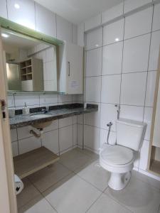 een witte badkamer met een toilet en een spiegel bij Vista espetacular da Praia de Iracema - Ap. 1405 in Fortaleza