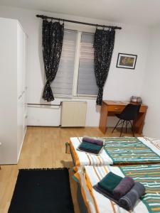 2 Betten in einem Zimmer mit einem Schreibtisch und einem Fenster in der Unterkunft Bagins Apartman in Kostolac