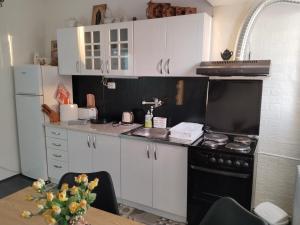 a kitchen with white cabinets and a black stove at Bagins Apartman in Kostolac