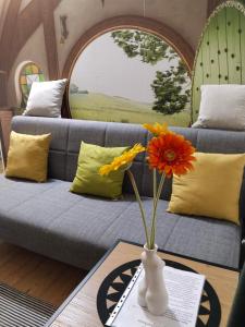 ein Wohnzimmer mit einem Sofa und einer Vase mit Blumen in der Unterkunft Bagins Apartman in Kostolac
