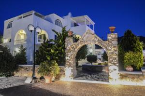 un grand bâtiment blanc avec une arche devant lui dans l'établissement Villa Anna Maria, à Mylopotas