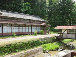 a building next to a road next to a river at Nakaya Ryokan in Kakeyu