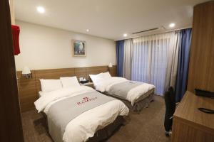 una camera d'albergo con 2 letti e una scrivania di Ramada Taebaek Hotel a Taebaek