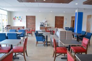 un comedor con mesas, sillas y mesa en Holiday Inn Express & Suites Raleigh Airport - Brier Creek, an IHG Hotel, en Raleigh