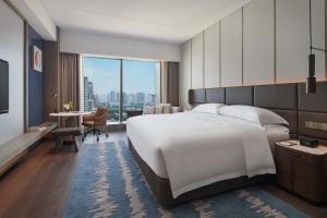 InterContinental Hotels Zhengzhou في تشنغتشو: غرفة نوم مع سرير أبيض كبير ومكتب