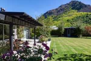 a garden with a house and mountains in the background at Kinsale - Spa, Pool, Gym and Tennis! in Arrowtown