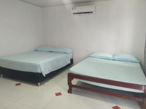 Duas camas num quarto com pisos brancos em Posada Sorybego em San Andrés