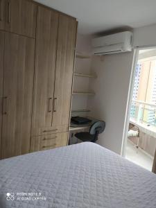 um quarto com uma cama, uma secretária e uma janela em Vista espetacular da Praia de Iracema - Ap. 1405 em Fortaleza
