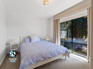 een slaapkamer met een bed en een groot raam bij Beautiful and peaceful house 500m to Knights beach in Port Elliot