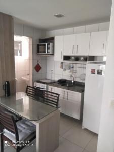 uma cozinha com armários brancos e um frigorífico branco em Vista espetacular da Praia de Iracema - Ap. 1405 em Fortaleza