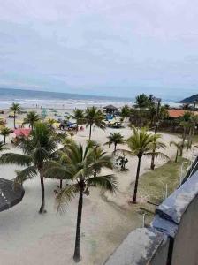 een uitzicht op een strand met palmbomen en de oceaan bij Sobrado moderno, piscina privativa, condomínio Morada da Praia! in Bertioga