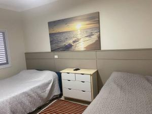 een slaapkamer met 2 bedden en een tv aan de muur bij Sobrado moderno, piscina privativa, condomínio Morada da Praia! in Bertioga