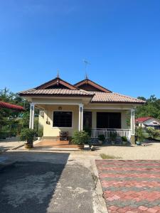 une petite maison blanche avec un toit en tuiles rouges dans l'établissement Homestay Nukman Bukit Besi, à Dungun