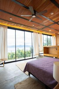 a bedroom with a ceiling fan and large windows at Estudio, vista increíble @serra in San Juan Cosalá