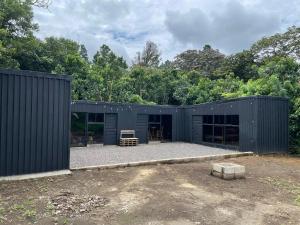 una casa negra con un patio frente a los árboles en Ricks hostel, en Juayúa