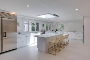 a white kitchen with a large island with bar stools at Cape Cod Home w/Ocean View, Roof Top, Pool & Hot Tub in Wellfleet
