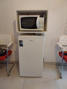 a microwave sitting on top of a refrigerator at Suíte Praia na casa da Berenice in Caraguatatuba