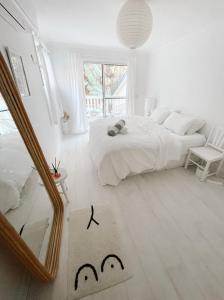 una camera bianca con letto e specchio di Cosy Home Byron Bay a Byron Bay