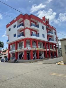 een rood-wit gebouw op de hoek van een straat bij Plataview Apartahotel 3B in Monte Plata
