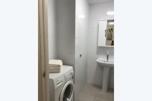 a white bathroom with a washing machine and a sink at شقة مريحة مع تكييف الهواء والتجديد in ‘Izbat al Kūbānīyah