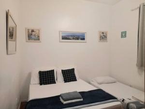 1 cama blanca con 2 almohadas y cuadros en la pared en Copacabana a 2 quadras da praia en Río de Janeiro