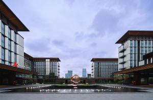 ein Gebäude mit einem Brunnen vor zwei Gebäuden in der Unterkunft Guangzhou Marriott Hotel Baiyun in Guangzhou