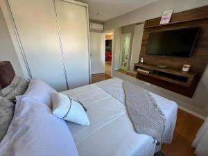 a white bed in a room with a flat screen tv at Apartamento em Canela perto da Catedral - Catedralle in Canela