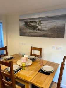 una mesa de madera con sillas y una pintura en la pared en Honeycomb Cottage, en Newburgh