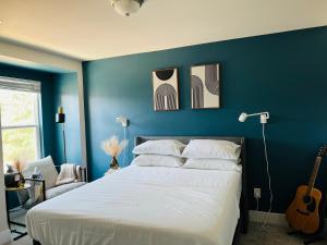 a bedroom with a blue wall with a bed and a guitar at Charlotte Comfort Haven in Charlotte