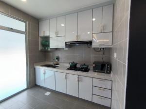 uma cozinha com armários brancos, um lavatório e um micro-ondas em Homestay Naufal Bandar Sri Sendayan Ground Floor em Seremban