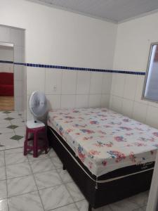 une chambre avec un lit, un ventilateur et un tabouret dans l'établissement Casa temporada Caípe fundo, à São Francisco do Conde