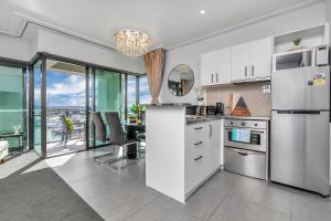 une cuisine avec des appareils électroménagers blancs et une table avec des chaises dans l'établissement Bachelor's Sunset Pad, à Auckland