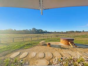 a fire pit in a field next to a fence at Waratah @ The Beltree in Belford