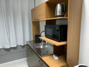 a kitchen with a microwave and a tv on a shelf at Studio 308 - Apartamento Passo Fundo in Passo Fundo