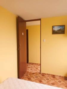 1 dormitorio con paredes amarillas y puerta con espejo en Pretty room in front of the Lima Airport, en Lima
